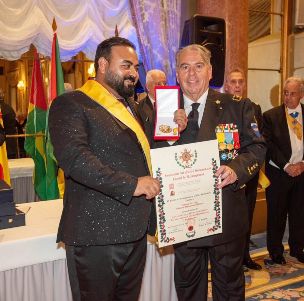 Dr. Waqas Nadeem receiving the Crown of Excellence and Crown of Humanity Awards at a humanitarian ceremony in Barcelona, representing Human Trust International’s global commitment to refugee welfare and education.